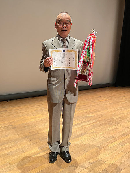 賞状とトロフィーを持つ諏訪智廣さんの写真