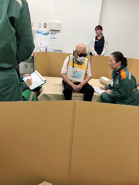段ボールで仕切られた空間で説明を受けている写真